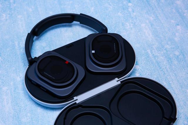 Black Nothing Pro 1 headphones sitting in an open case on a texture blue background.