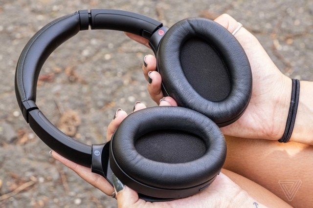 A person holding a pair of Sony WH-1000XM4 headphones.