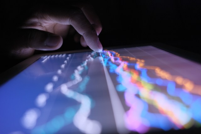 close up of man hand with digital tablet analyzing stock market graph at night