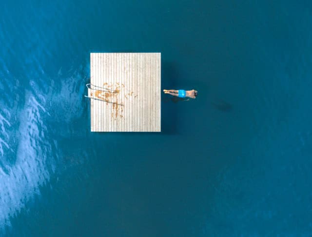Image of a man jumping from a floating dock into a lake.