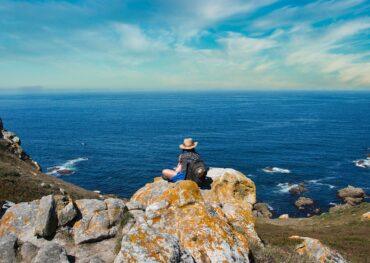 Seaside view of cliffs in Asturias with a woman enjoying the ocean scenery.