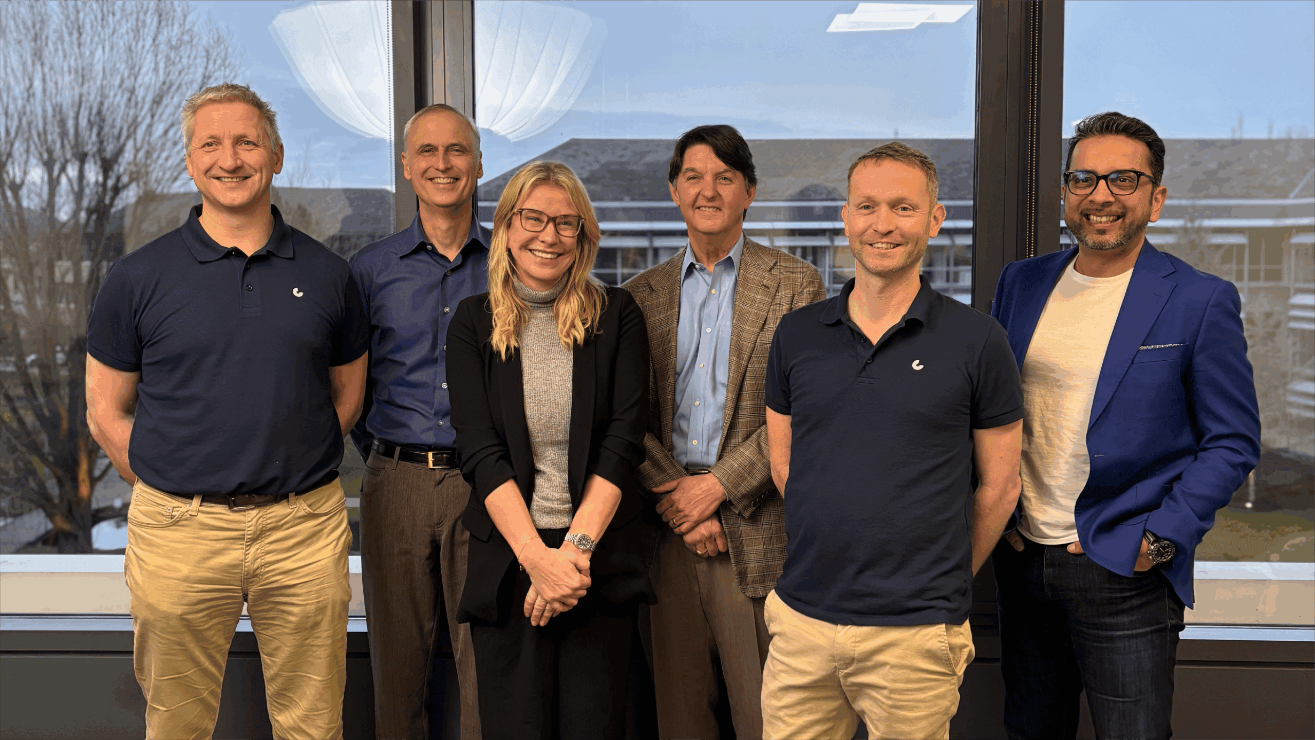 Group of six people smiling in office setting.