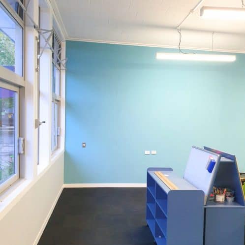 Modern classroom with blue wall, large windows, and minimal furnishings, ideal for learning and teaching environments.