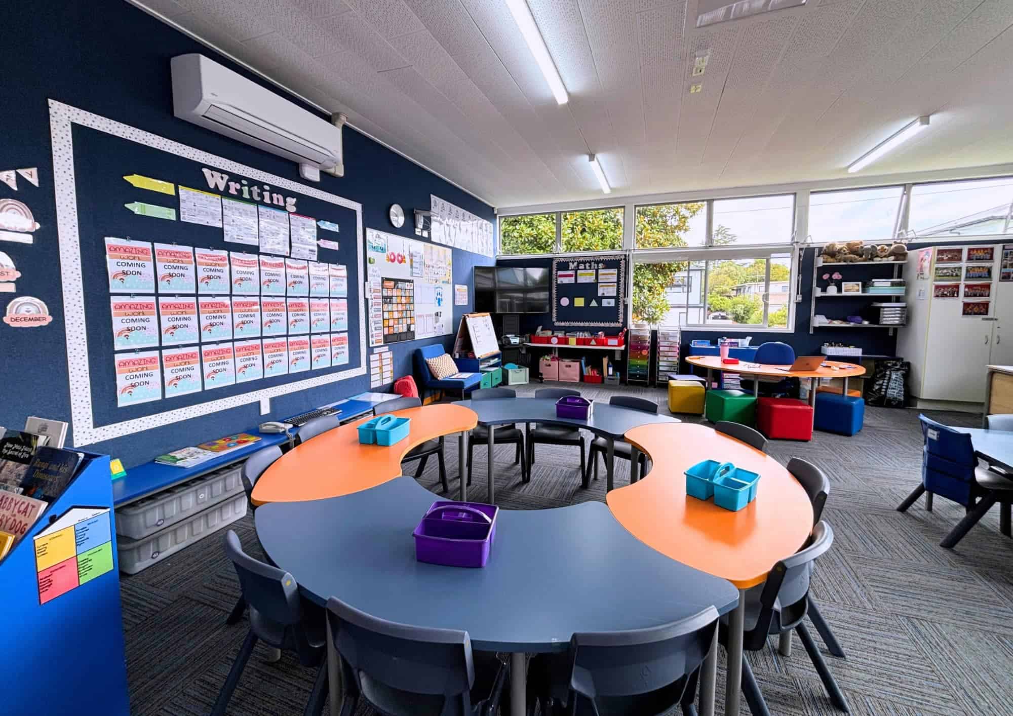 Bright and vibrant classroom setup for early childhood education featuring colorful tables, chairs, and educational wall displays at Keola childcare centre, New Zealand.