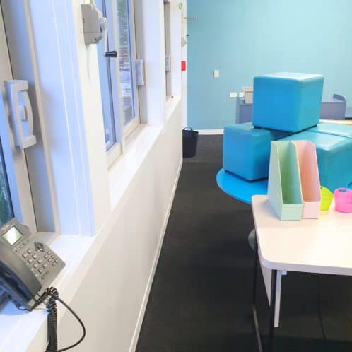 Bright interior of a modern childcare or activity centre with colourful soft play equipment and a white table with pastel storage containers, ideal for early childhood education spaces.