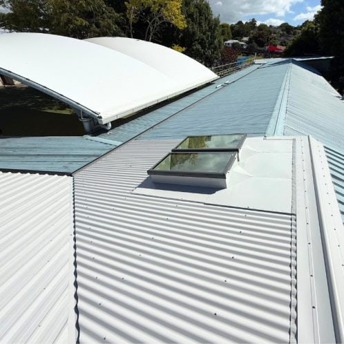 Bright white steel roofing on a commercial building with skylights and curved roofing sections, showcasing durable, weather-resistant roofing solutions by Keola in New Zealand.