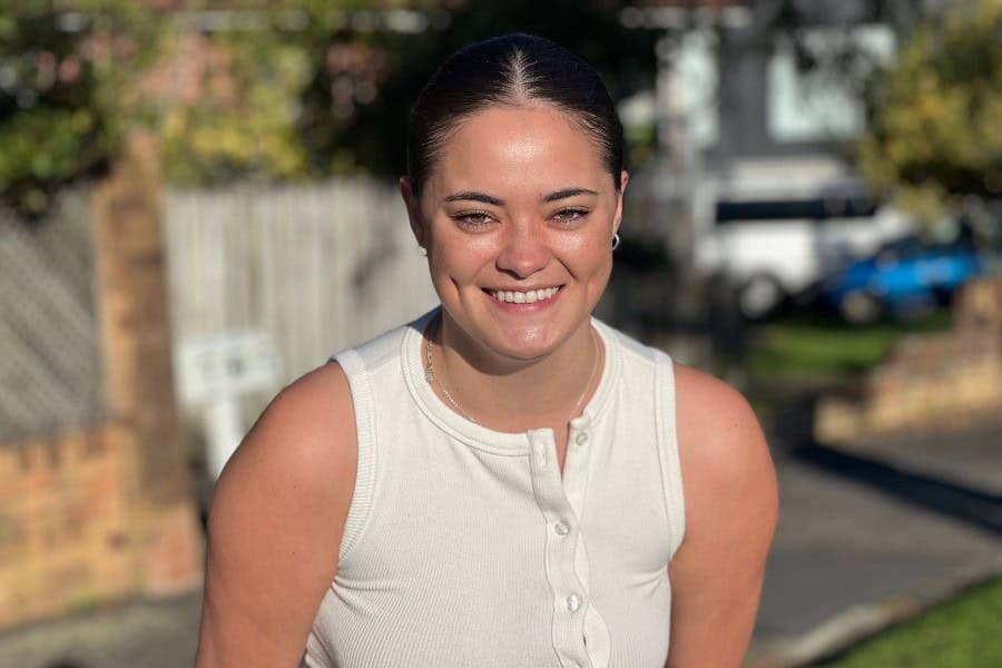 Bright smiling woman outdoors in sunlight, casual white sleeveless top, natural setting, happy and relaxed vibe, perfect for lifestyle and wellness themes.
