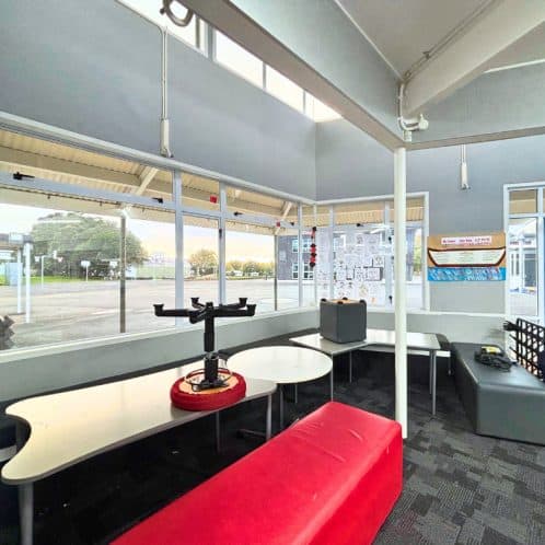 Sunny indoor waiting area at New Zealand train station with large windows, seating, and modern decor.