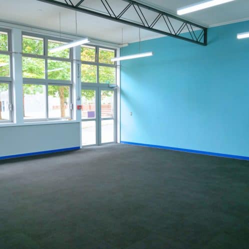 Bright spacious indoor area with large windows, blue accent walls, and commercial flooring for versatile use. Perfect for community activities, events, or business functions in New Zealand.