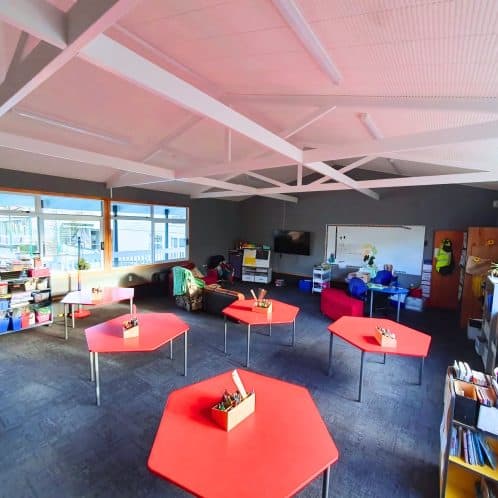 Bright classroom interior at Keola early childhood centre in New Zealand, featuring colourful tables, educational materials, and learning areas for children.