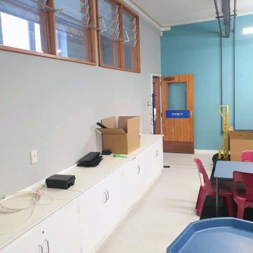 Bright indoor educational or community space with storage cabinets, colorful chairs, and a blue table, ideal for activities, meetings, or learning environments.