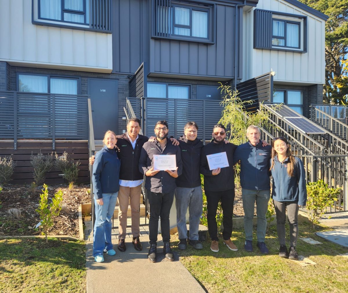 Professional team celebrating home construction completion at Keola residential complex, showcasing quality craftsmanship and customer satisfaction in New Zealand.