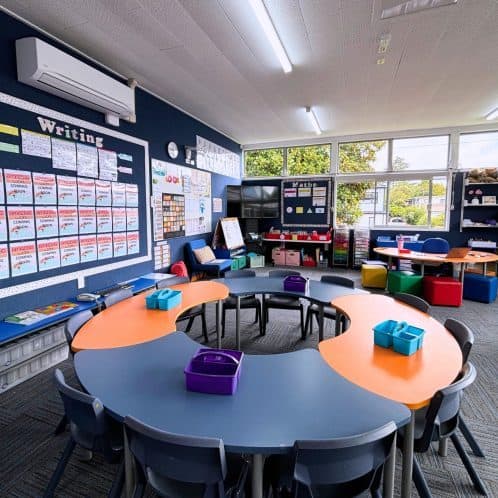 Bright and vibrant classroom setup for early childhood education featuring colorful tables, chairs, and educational wall displays at Keola childcare centre, New Zealand.