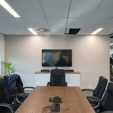 Modern corporate meeting room with a large wooden table, ergonomic chairs, and a flat-screen television for presentations and video conferences. Perfect for professional business meetings.