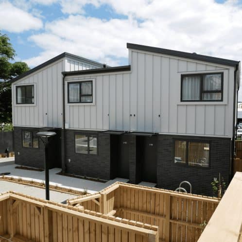 Modern residential townhouse with minimalist black and white exterior design, featuring large windows and a landscaped front yard in Auckland, NZ.