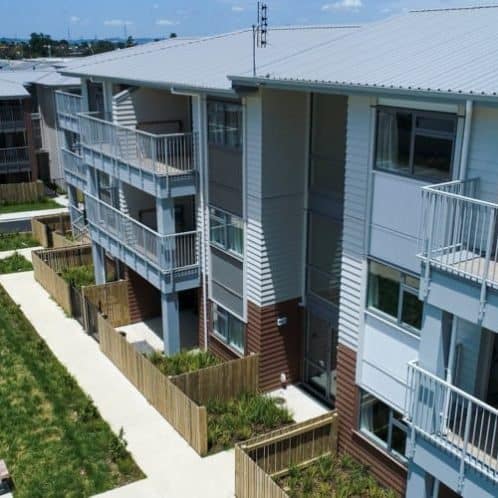 Modern apartment complex with balconies and landscaped courtyard in New Zealand.