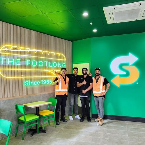 Keola team standing inside the completed Subway Fresh Forward 2.0 store beside the illuminated Footlong feature wall.