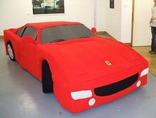 Ferrari sports car made from red felt fabric, displayed indoors at an event or exhibition in New Zealand.