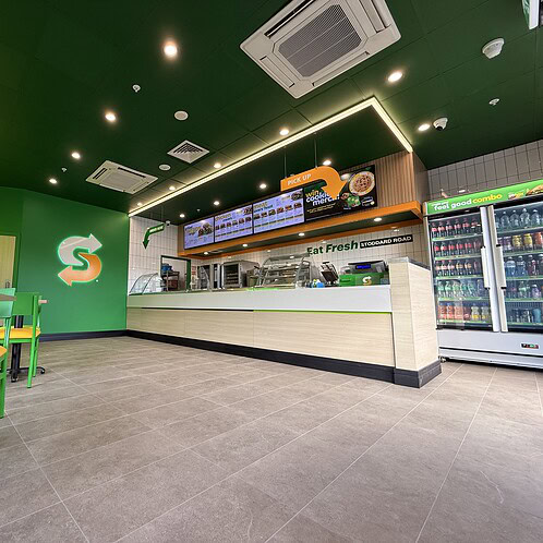 Wide-angle view of the completed Subway Fresh Forward 2.0 fitout showing seating, counter area, menu boards and feature lighting.