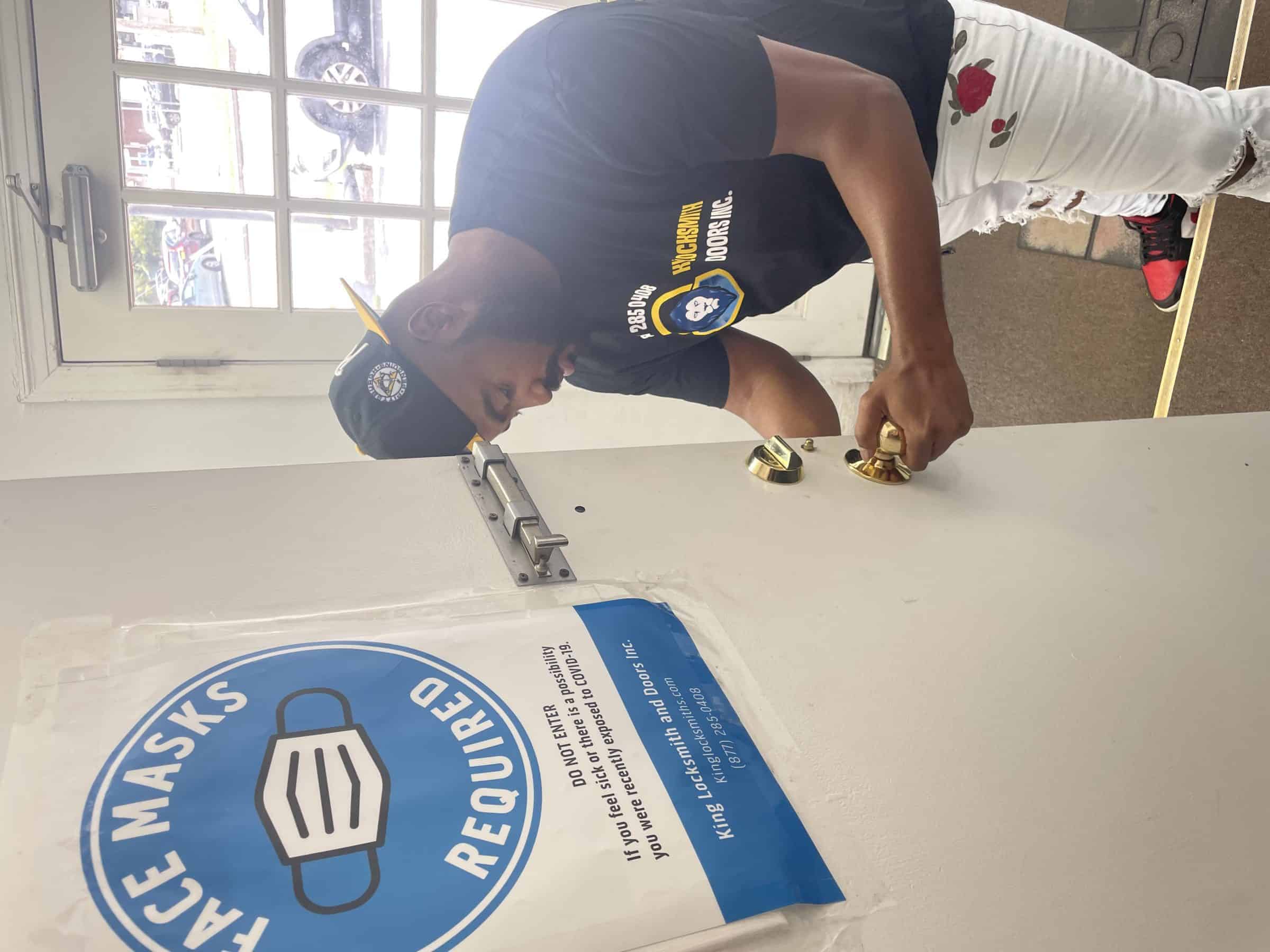 Featuring A Skilled Technician With Black Uniform And Cap Performing Door Lock Repair Services With Precision And Expertise.