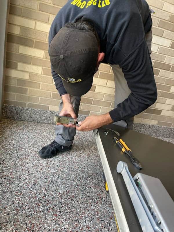 A Locksmith In Uniform Repairing Door Hinges. Locksmith Near Me