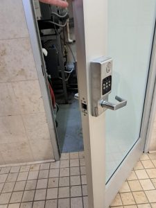 A Partially Open Glass Door With A Keypad Door Lock, Showcasing Door Lock And Repair.