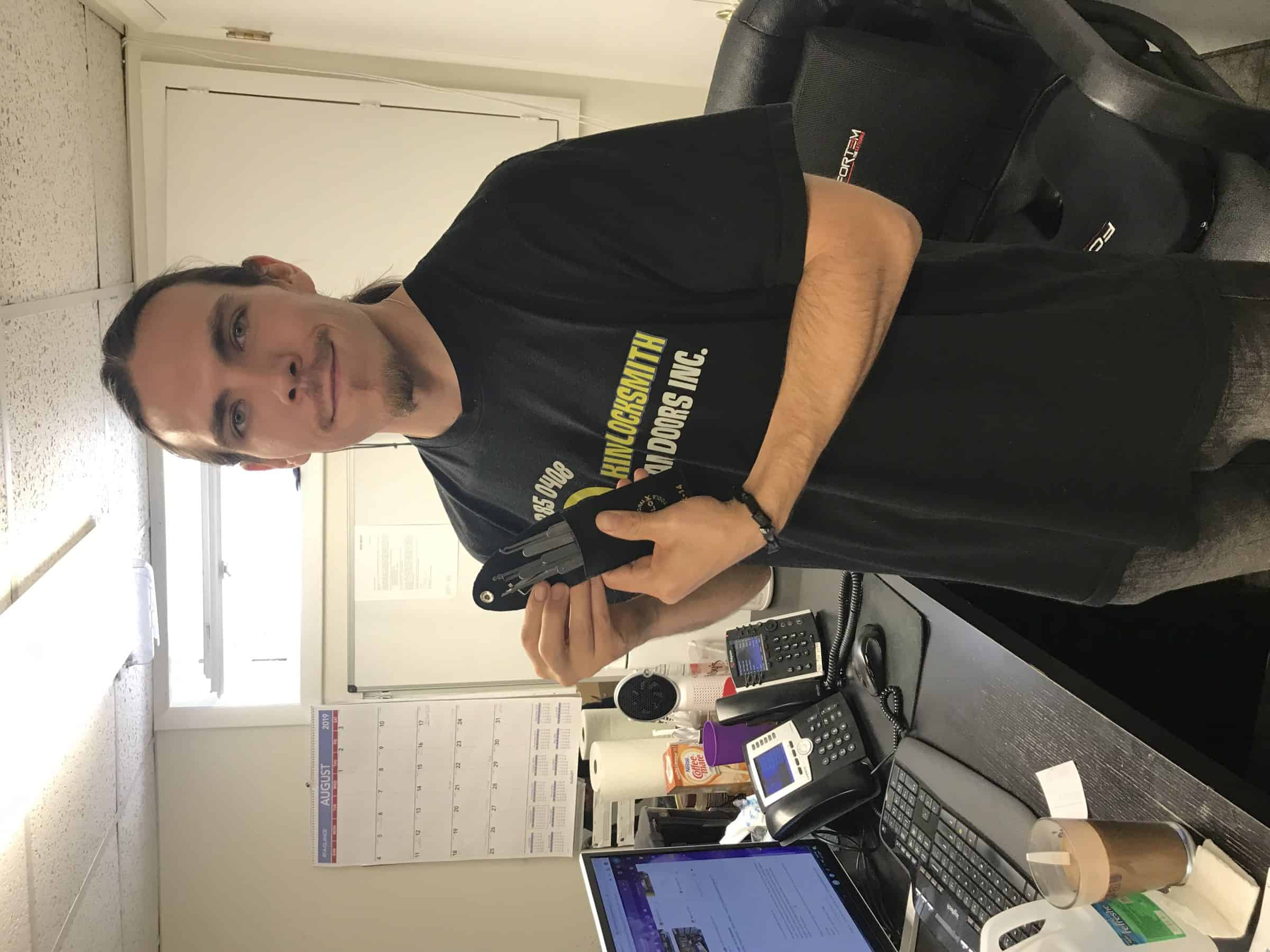 A Locksmith In A Black Uniform Displaying Various Tools, Prepared For Anyone Searching For &Quot;Locksmith Near Me&Quot;