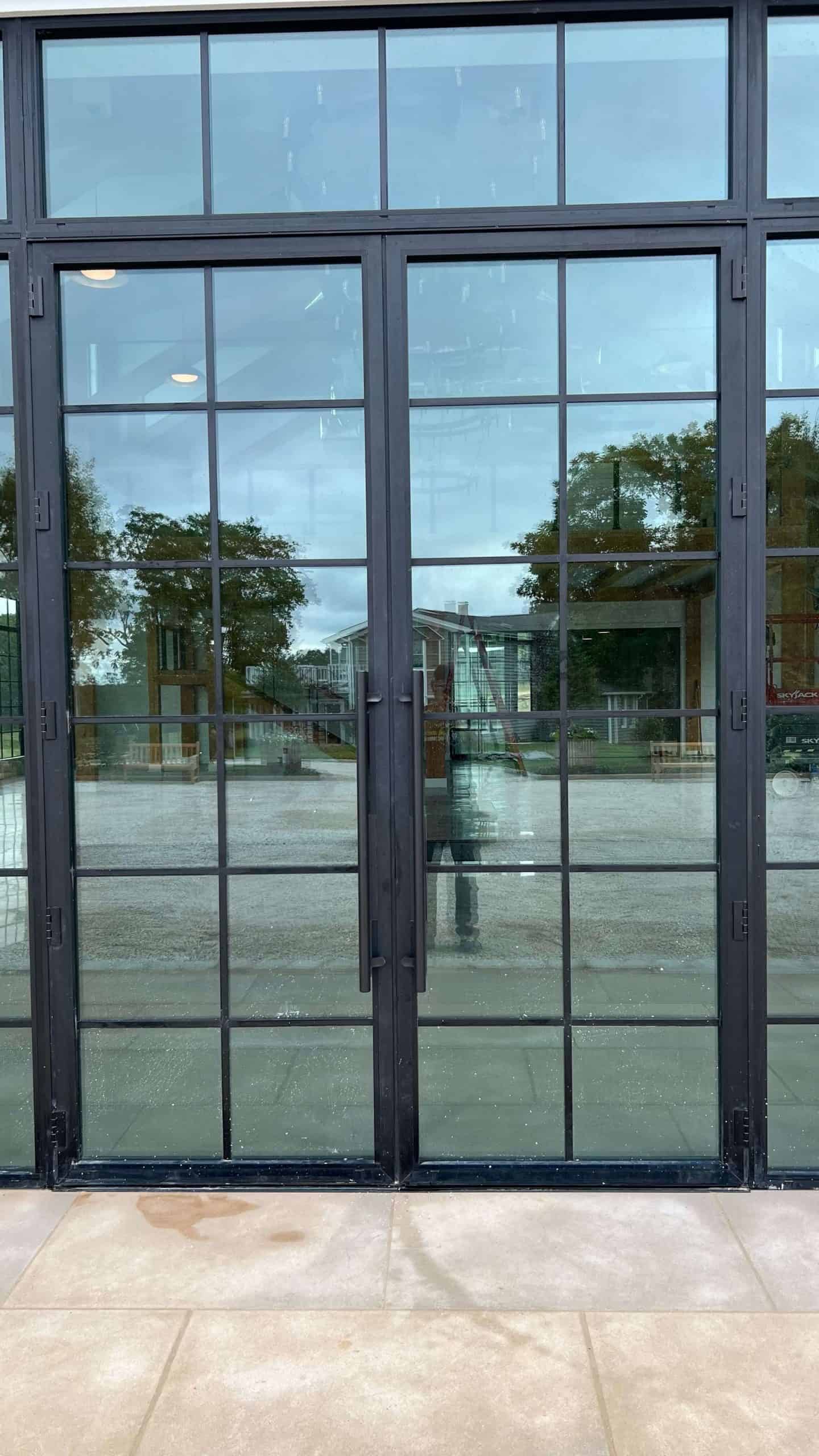 A Glass Door With Black Mullions And Rail, Indicative Of Commercial Locksmith Services.