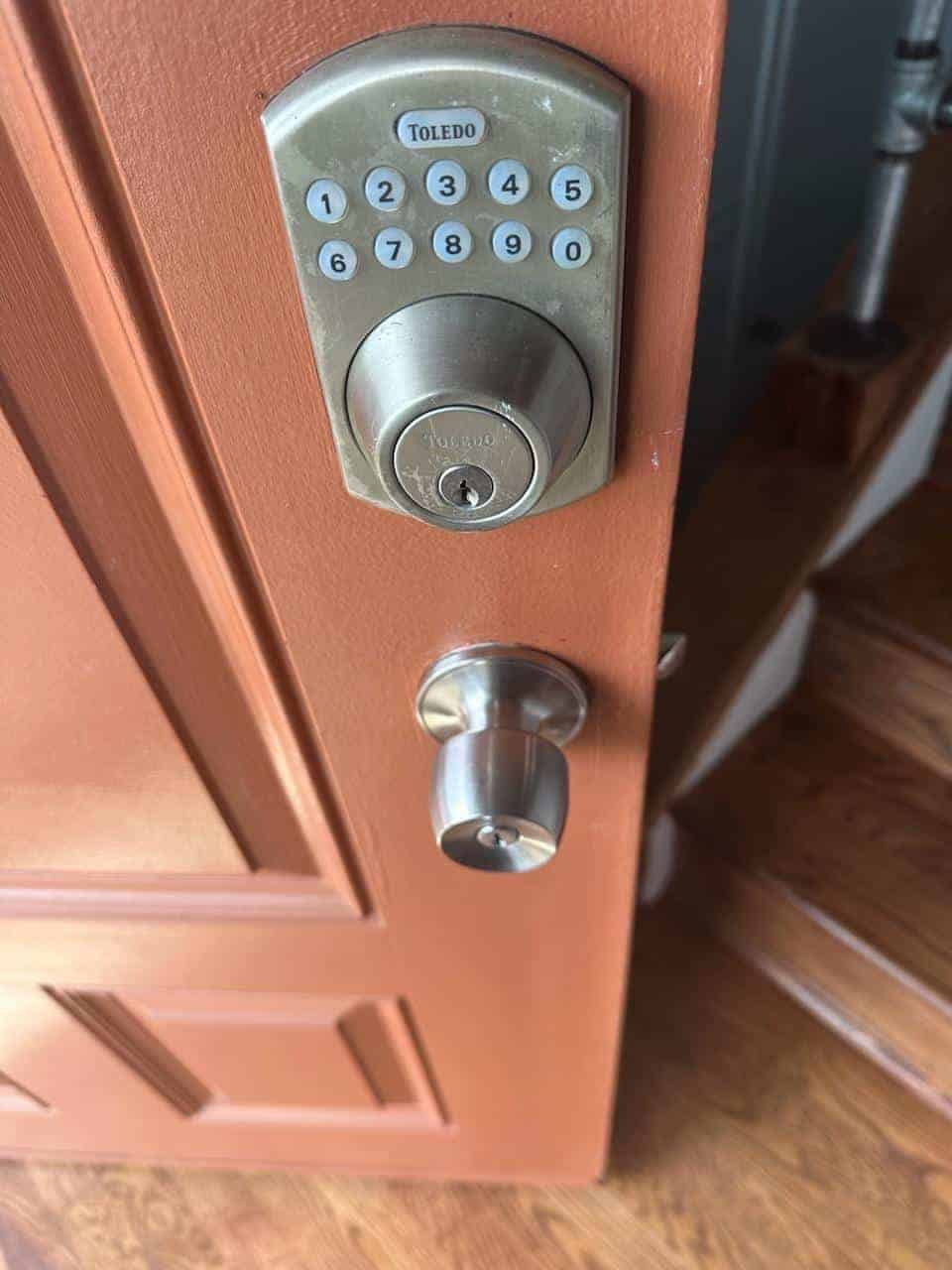 A Maple Door Featuring A Silver Keyless Entry Lock And A Door Knob.