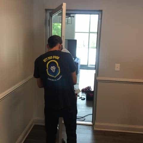 A Locksmith Bethesda Md In A Black Uniform Facing Towards The Door, Ready To Provide Locksmith Services.
