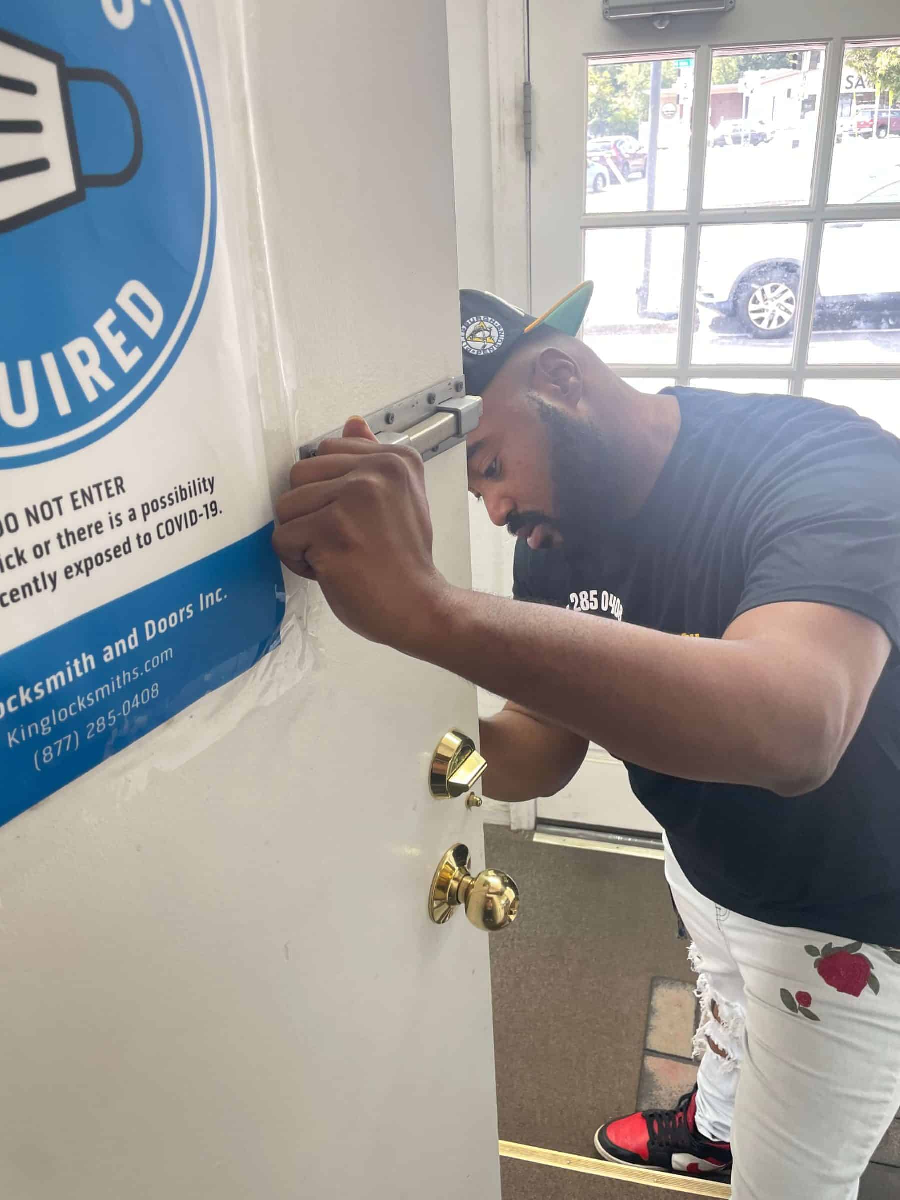 A Locksmith From Locksmiths 24/7 Repairing A White Door With A Golden Door Knob.