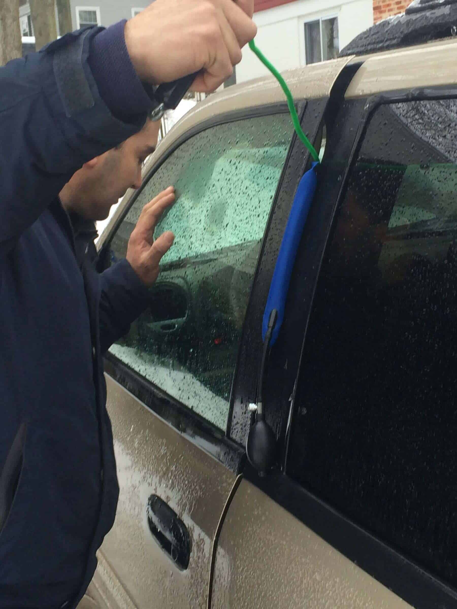 Auto Locksmith Baltimore A Locksmith In Baltimore Is Using Professional Tools To Unlock A Car In The Rain.