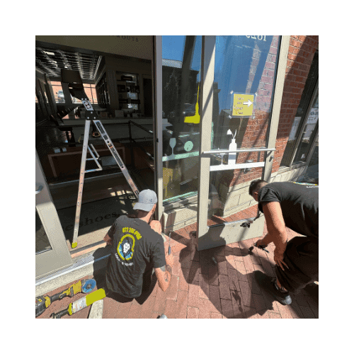 Two Locksmiths In Black Repairing The Storefront Door In Germantown Md