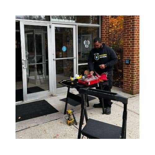 Technician From King Locksmith And Doors Inc. Repairing An Ada-Compliant Door At A Commercial Building Entrance In Catonsville Md, Showcasing Tools And Equipment For Professional Door Repair Services.