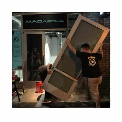 Aluminum Door Repair In Gaithersburg Maryland Two Locksmiths From King Locksmith And Door Inc. Lifting An Aluminum Door For Installation After Completing Repairs In Gaithersburg