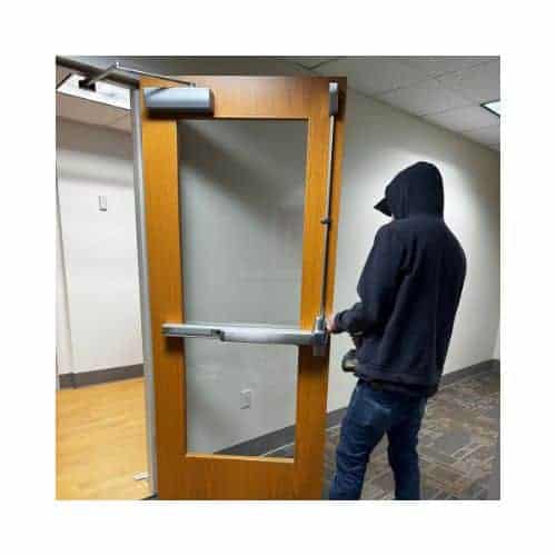 King Locksmith'S Technician Replacing A Door Closer On A Wooden Door With A Glass Panel, Equipped With A Panic Bar Mechanism, In A Commercial Building Hallway In Burtonsville Maryland