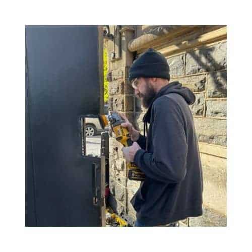 A Locksmith Of King Locksmith And Doors Inc Installing A Steel Door, Grinding Parts To Prepare For The Door Latch Installation
