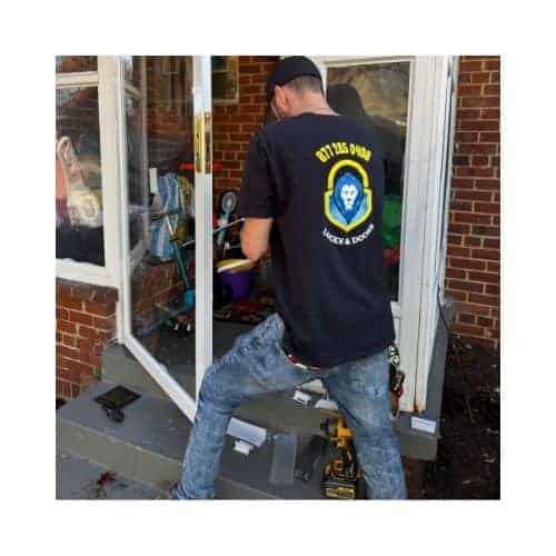 A Residential Locksmith Glen Burnie Md From King Locksmith Doors Inc., Wearing A Black Uniform With The Contact Number Printed On The Back, Repairing A Storm Door In Glen Burnie Md Using Complete Tools.
