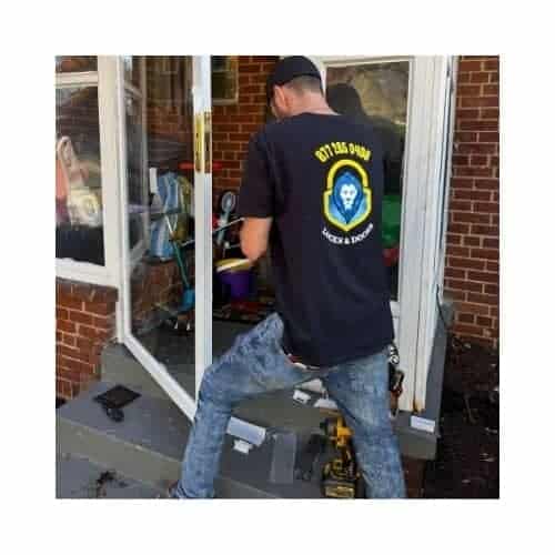 A Locksmith From King Locksmith Doors Inc., Wearing A Black Uniform With The Contact Number Printed On The Back, Repairing A Storm Door In Jessup Md Using Complete Tools.