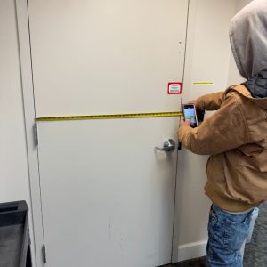 Our Locksmith Severn Md Measuring A Commercial Door For Lock Installation Highlighting Business Security Solutions.