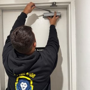 A Locksmith Adjusting An Overhead Door Closer, Offering Reliable Emergency Locksmith Solutions In Fort Meade, Md.