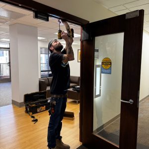 Our Commercial Locksmith Fort Meade Working On A Commercial Door Frame, Demonstrating Expertise In Advanced Lock Installations.