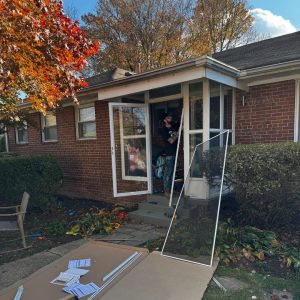 Residential Locksmith Anne Arundel Installing A Glass Storm Door For A Brick Home In A Suburban Setting.