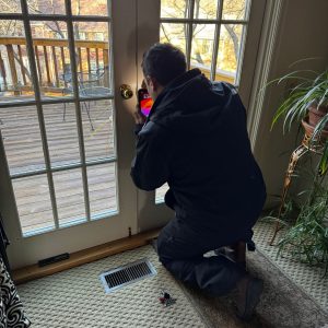 A Locksmith Working On A Residential Glass Door Lock In Severn, Md, Showcasing Professional Lock Repair Services.
