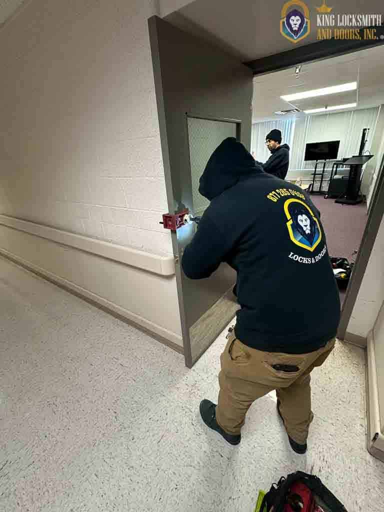 Commercial locksmith installing panic bar hardware on interior metal door in Jessup Maryland facility