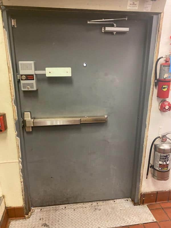 Commercial metal exit door with panic bar and door closer installed in Ellicott City MD building