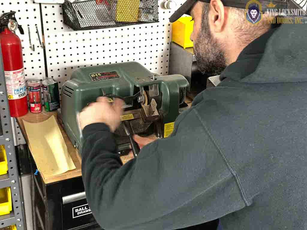 Professional locksmith cutting and calibrating key during structured rekey process with inspection and mechanical verification in Silver Spring MD.