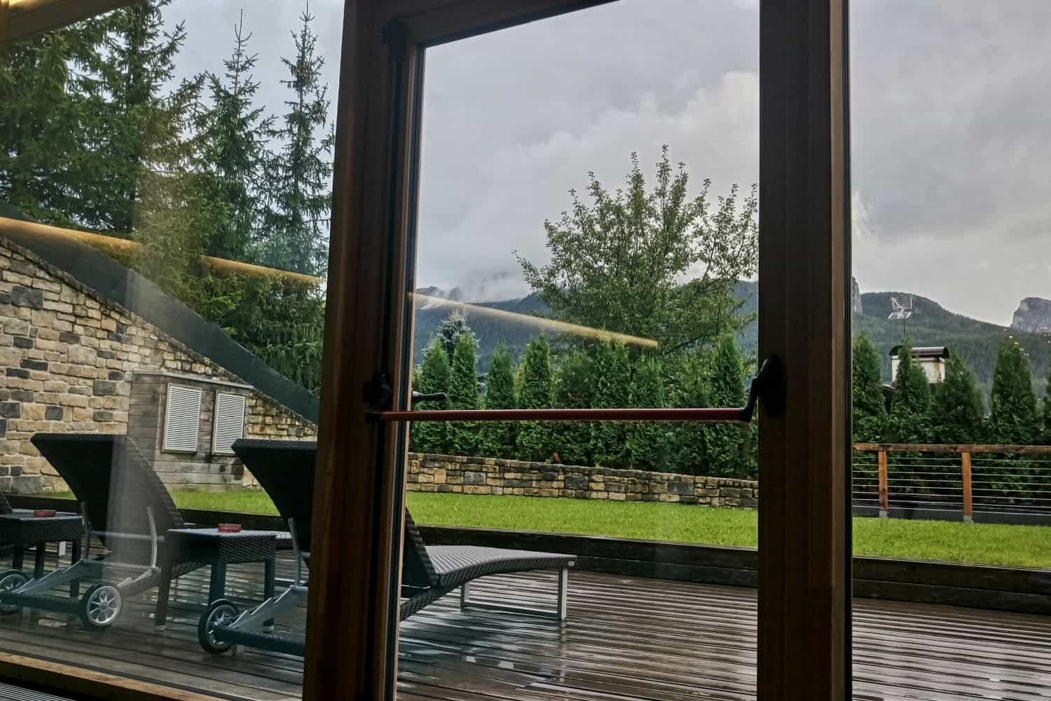 view of a garden, rainy terrace, and mountains from a spa in hotel lajadira and spa cortina d ampezzo in the dolomites