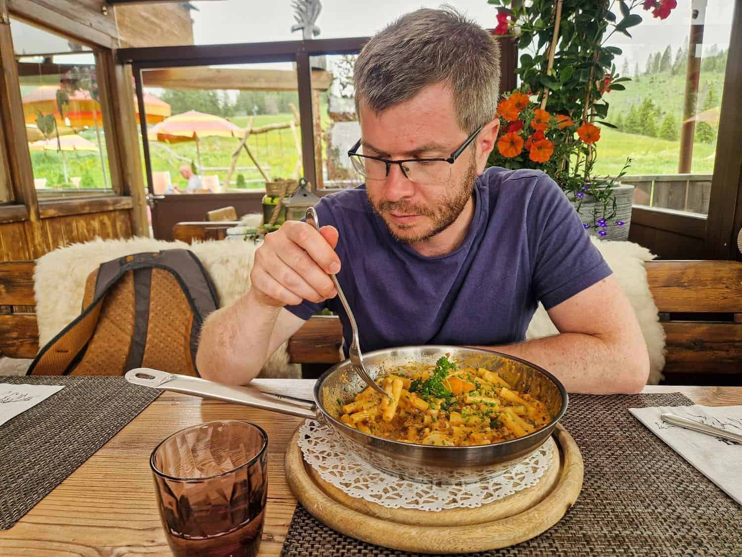 michal eating a traditional pasta dish from a pan in the dolomites