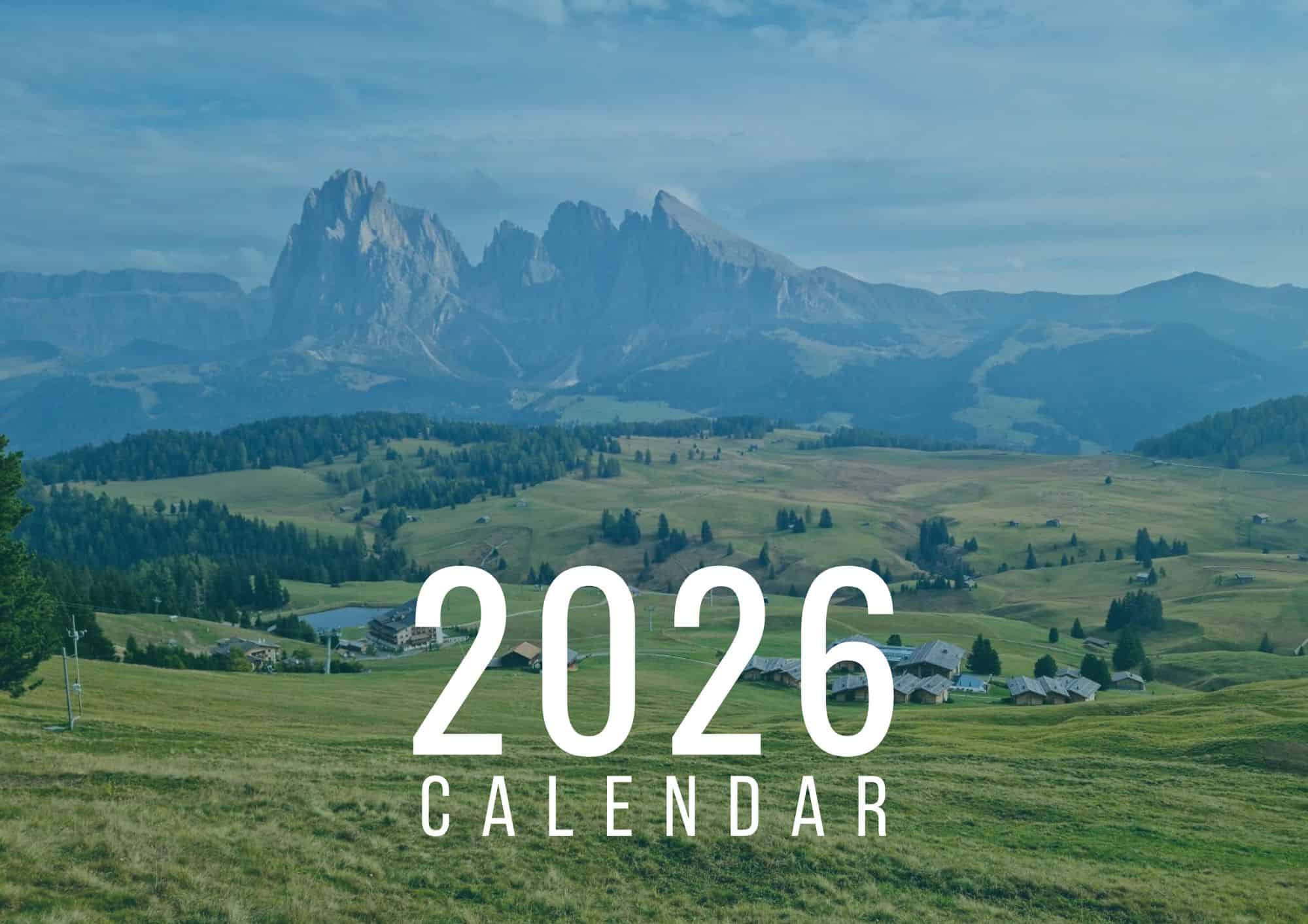 A scenic mountain landscape with green rolling hills, scattered houses, and dramatic rocky peaks in the background. Large white text in the foreground reads “2026 Calendar.”.